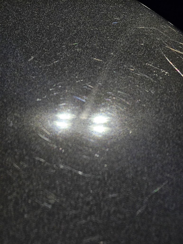 Close-up of black car paint with moderate swirl marks